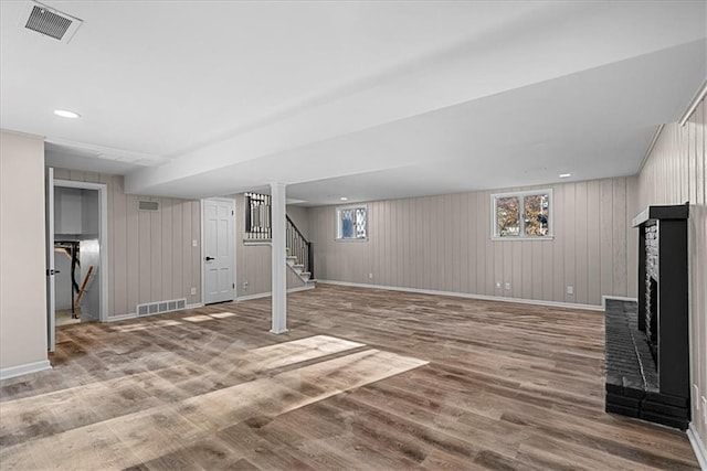 basement with a fireplace, hardwood / wood-style floors, and wood walls