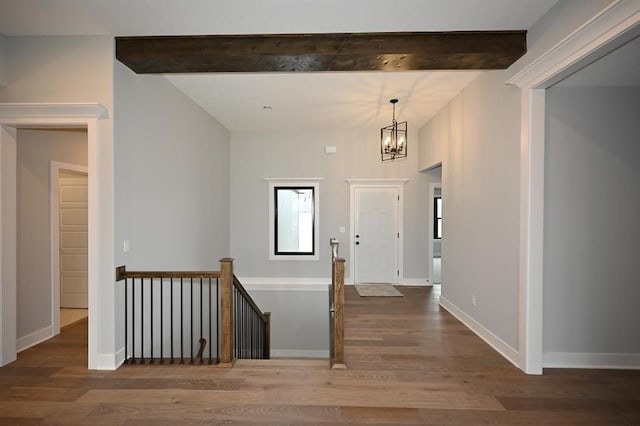 foyer entrance featuring beamed ceiling, wood finished floors, and a chandelier