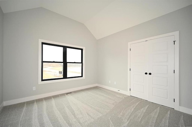 spare room with vaulted ceiling, baseboards, and carpet floors