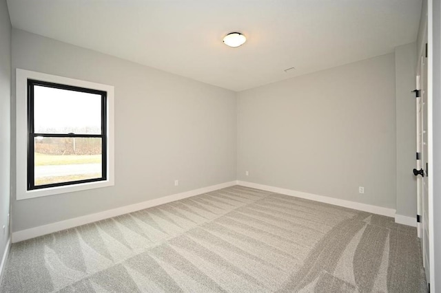 carpeted empty room featuring baseboards