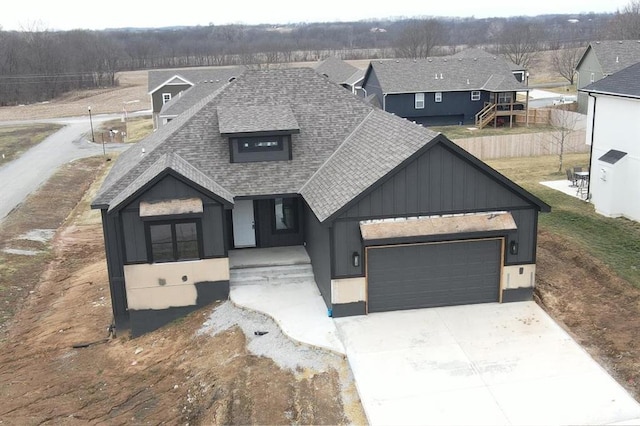 view of front facade featuring a garage, roof with shingles, driveway, and fence