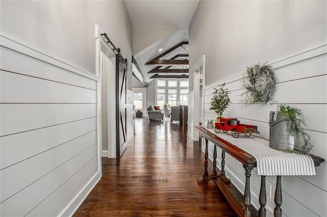 hall with dark hardwood / wood-style floors, a barn door, and beam ceiling