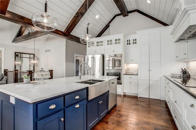 kitchen with decorative backsplash, appliances with stainless steel finishes, blue cabinets, sink, and pendant lighting