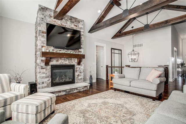 living room with a chandelier, dark hardwood / wood-style flooring, vaulted ceiling with beams, and a stone fireplace