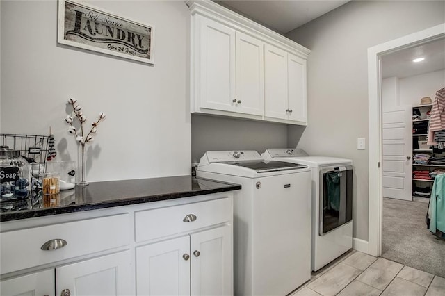 clothes washing area featuring cabinets, light colored carpet, and washing machine and clothes dryer