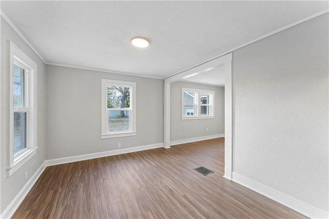 spare room with crown molding, plenty of natural light, and hardwood / wood-style floors