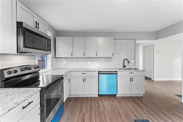 kitchen with light stone counters, stainless steel appliances, sink, white cabinets, and dark hardwood / wood-style floors