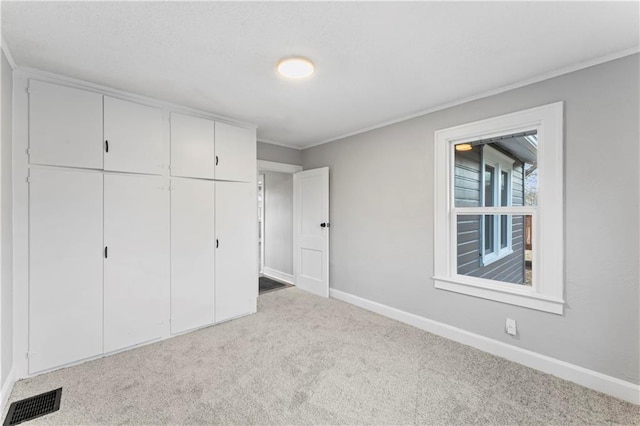 unfurnished bedroom with ornamental molding, light carpet, and a closet