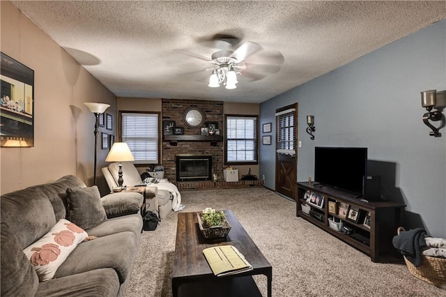 living room featuring carpet flooring, ceiling fan, a textured ceiling, and a brick fireplace