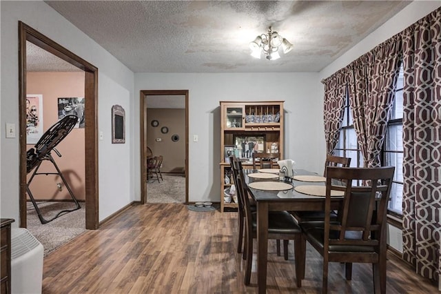 dining room with hardwood / wood-style floors, a notable chandelier, and a textured ceiling