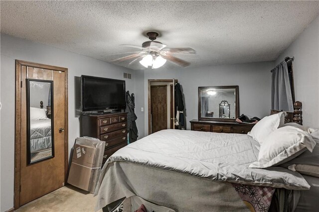 bedroom featuring ceiling fan, light colored carpet, and a textured ceiling