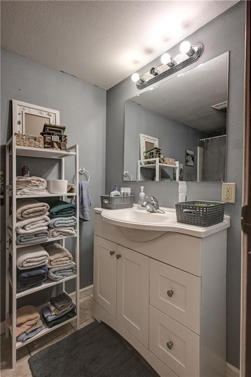 bathroom featuring a textured ceiling, vanity, and walk in shower