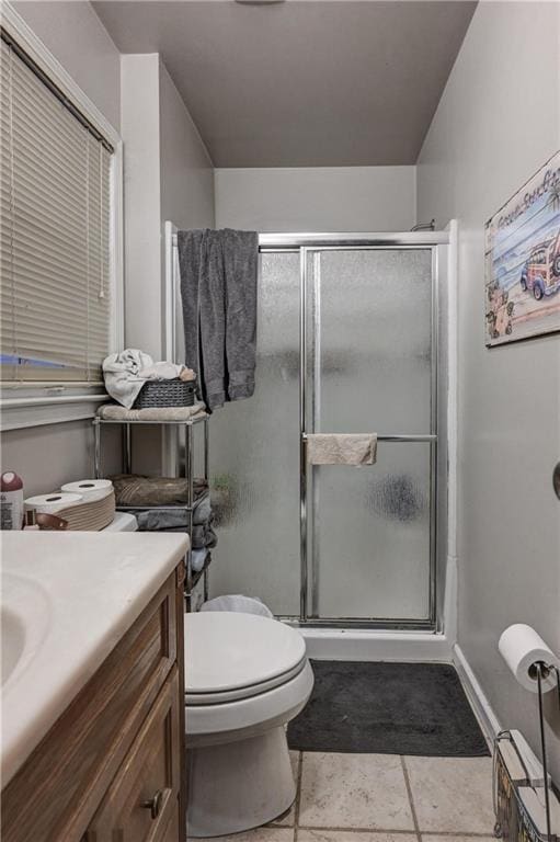 bathroom with tile patterned flooring, vanity, toilet, and a shower with door