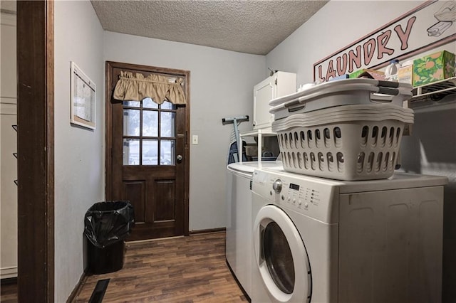 laundry room featuring a textured ceiling, washer and clothes dryer, cabinets, and dark hardwood / wood-style floors