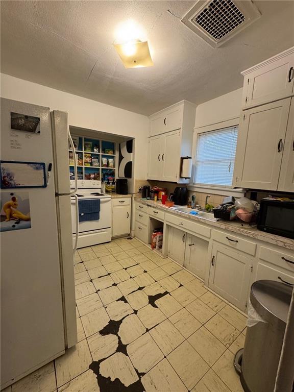 kitchen with white cabinetry, sink, white appliances, and a textured ceiling