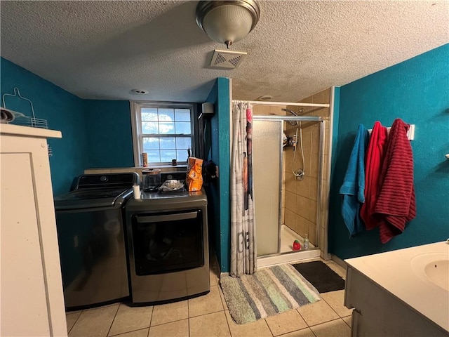 laundry area featuring sink, light tile patterned floors, washer and dryer, and a textured ceiling