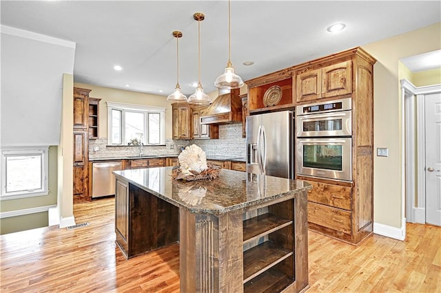 kitchen featuring sink, decorative light fixtures, dark stone countertops, a kitchen island, and stainless steel appliances