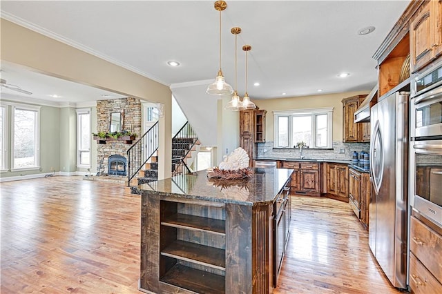 kitchen with pendant lighting, dark stone countertops, a center island, decorative backsplash, and light wood-type flooring