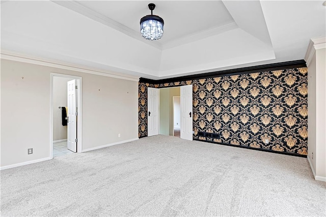 spare room with crown molding, a raised ceiling, a chandelier, and light carpet