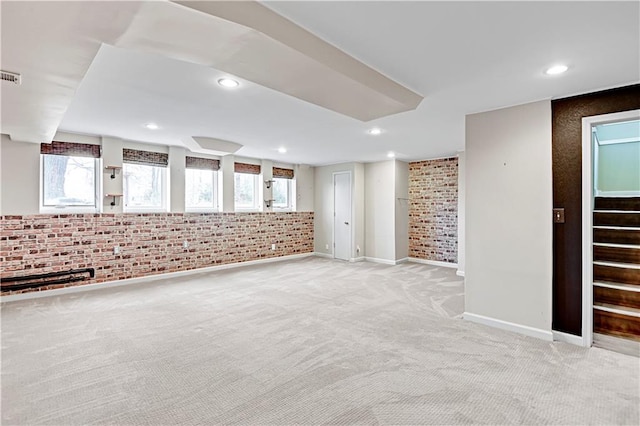 carpeted spare room featuring brick wall