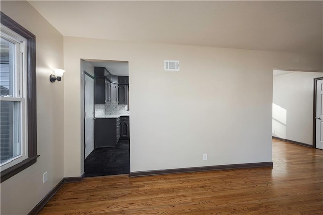 empty room featuring a wealth of natural light and dark wood-type flooring