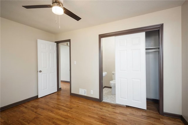 unfurnished bedroom with connected bathroom, ceiling fan, a closet, and hardwood / wood-style floors