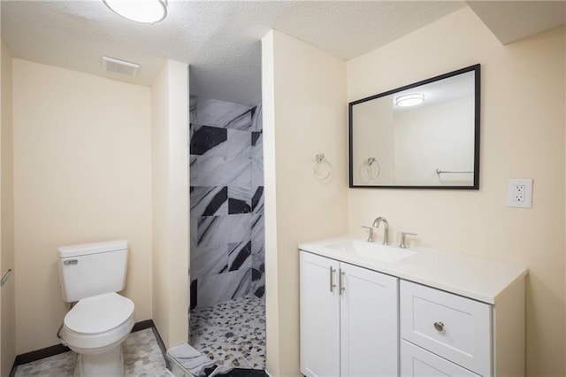 bathroom with toilet, vanity, a textured ceiling, and walk in shower