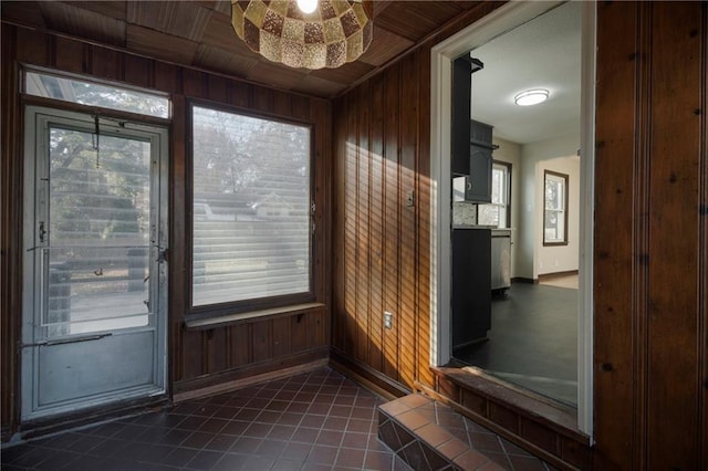 doorway featuring dark tile patterned flooring, ceiling fan, wooden ceiling, and wood walls