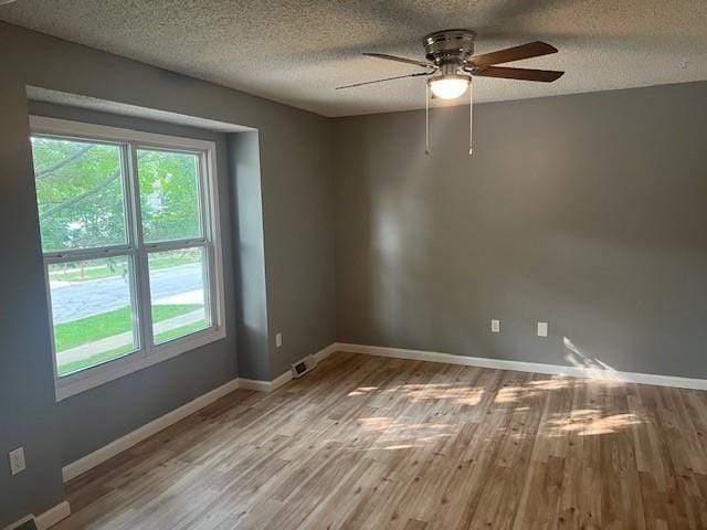 spare room featuring a textured ceiling, light hardwood / wood-style flooring, and ceiling fan