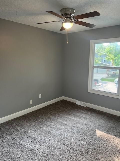 carpeted spare room featuring ceiling fan and a textured ceiling