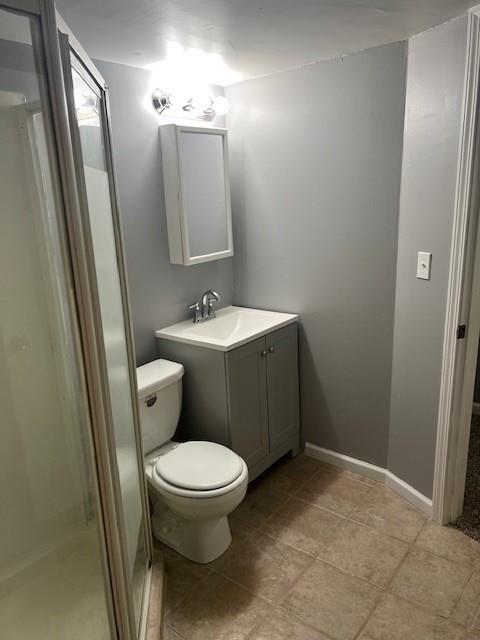 bathroom with tile patterned floors, vanity, toilet, and a shower with shower door