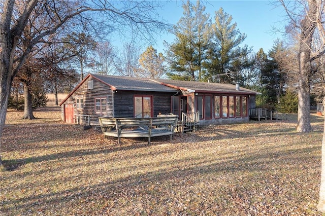 view of front facade featuring a front yard, a deck, and a sunroom