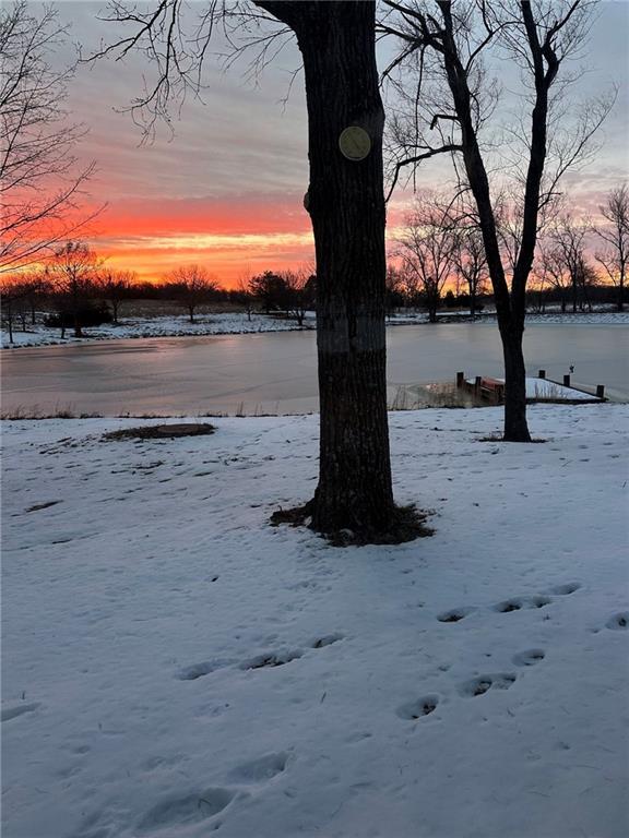 yard layered in snow featuring a water view