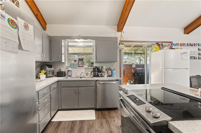 kitchen with beamed ceiling, appliances with stainless steel finishes, sink, and gray cabinetry