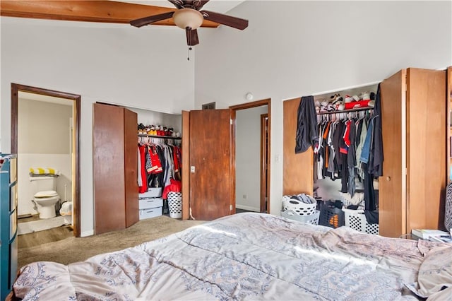 bedroom with ceiling fan, ensuite bath, multiple closets, and lofted ceiling