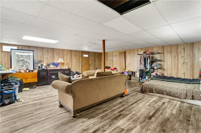 living room featuring wood walls, hardwood / wood-style floors, and a drop ceiling