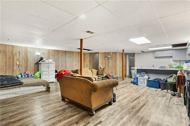 living room with wood walls, hardwood / wood-style floors, and a drop ceiling