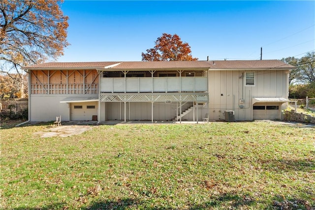 back of property featuring a garage, a yard, and cooling unit