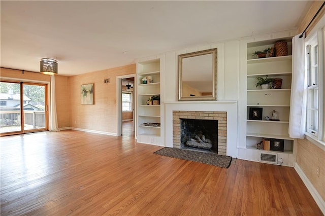 unfurnished living room with a fireplace, light hardwood / wood-style flooring, and built in features