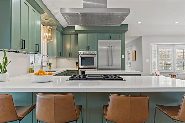 kitchen featuring a breakfast bar, green cabinetry, hanging light fixtures, stainless steel appliances, and range hood