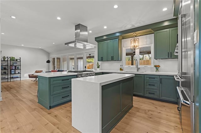 kitchen featuring sink, island range hood, green cabinets, a kitchen island, and stainless steel appliances