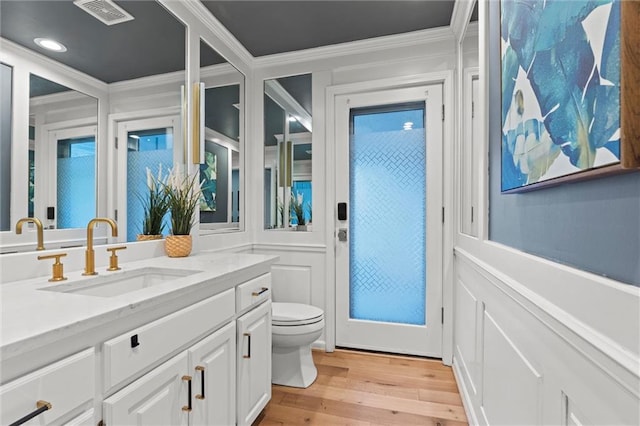 bathroom with hardwood / wood-style flooring, crown molding, vanity, and toilet