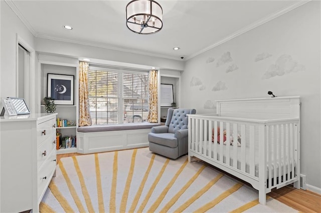 bedroom with a nursery area, ornamental molding, and light hardwood / wood-style flooring