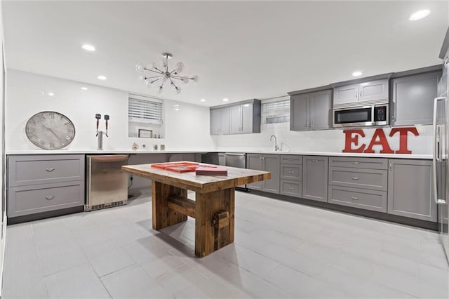 kitchen featuring sink, gray cabinetry, a chandelier, light tile patterned floors, and fridge