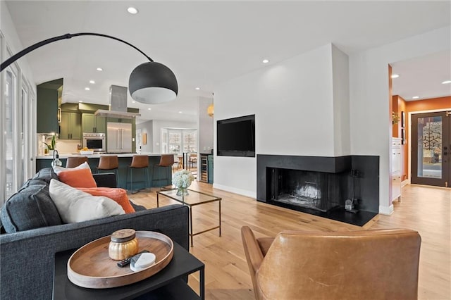 living room featuring a multi sided fireplace, beverage cooler, light hardwood / wood-style floors, and french doors