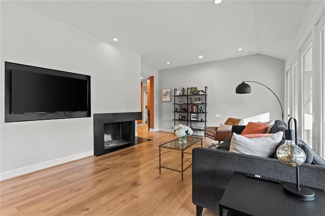 living room featuring a multi sided fireplace, vaulted ceiling, and light hardwood / wood-style flooring