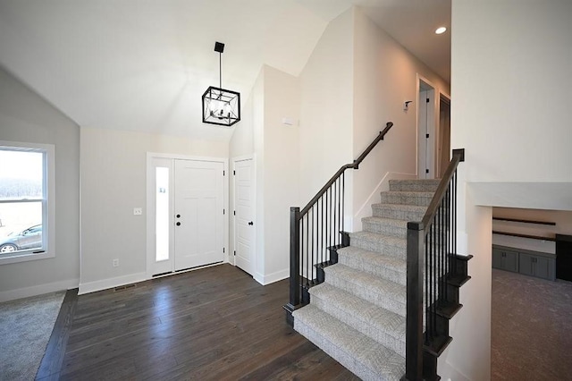 entryway with a chandelier, dark hardwood / wood-style flooring, and vaulted ceiling