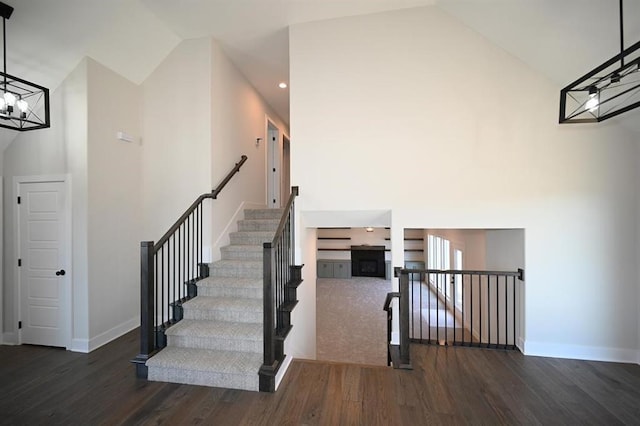 stairs featuring hardwood / wood-style flooring and high vaulted ceiling