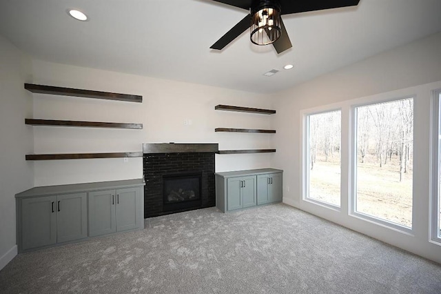 unfurnished living room with light carpet, a brick fireplace, and ceiling fan