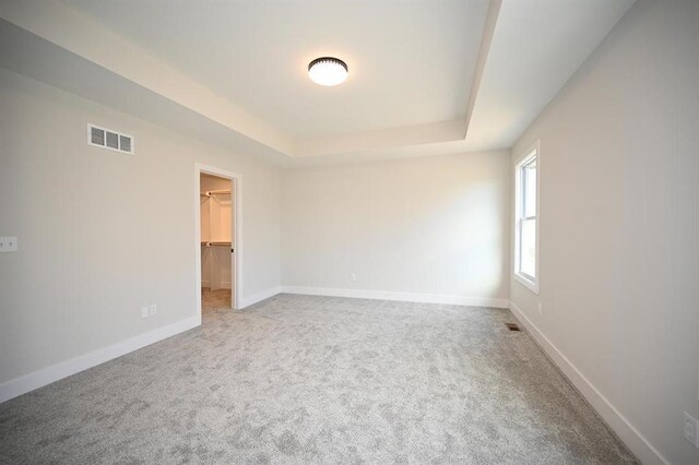 carpeted spare room featuring a tray ceiling